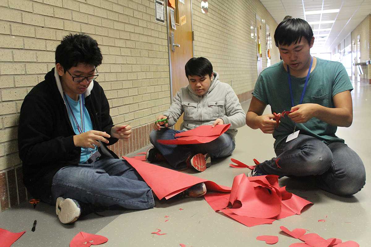 Sophomore Kevin Le and juniors Kevin Nguyen and Don Nguyen create decorations and notes for to put on the wall in I Hall.